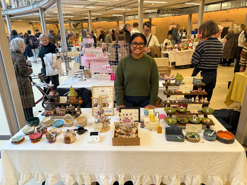Handmade ceramic mugs and objects displayed at a local market stall