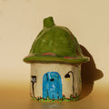 handmade ceramic incense holder shaped like a small moss house with green roof and chimney
