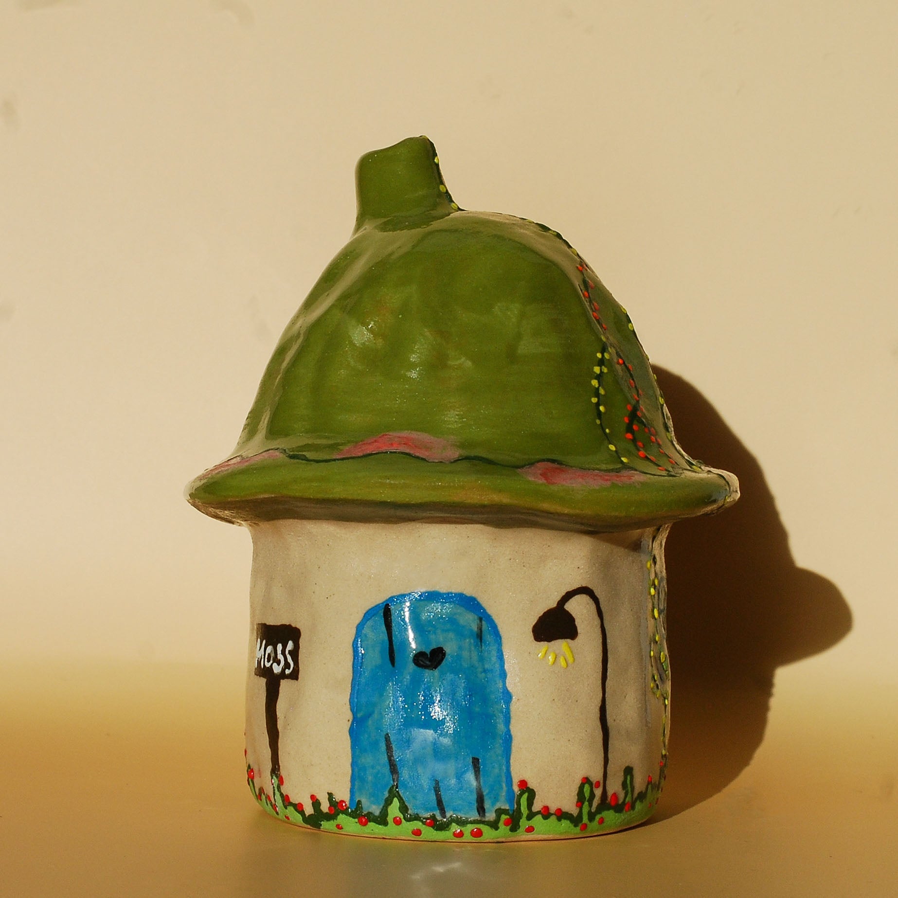handmade ceramic incense holder shaped like a small moss house with green roof and chimney