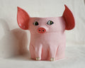A pink pig-shaped planter with large floppy ears, painted eyes, and small hooves, photographed against a plain light background.
