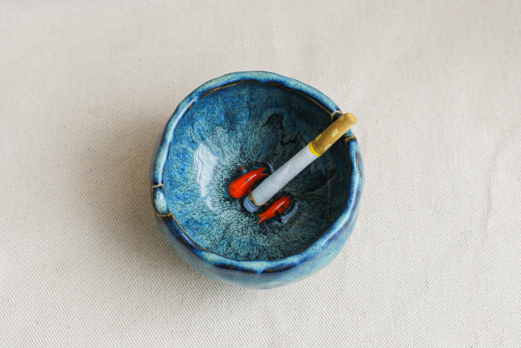 Blue ceramic ashtray with koi fish inspired by a midnight scene kept on a beige background