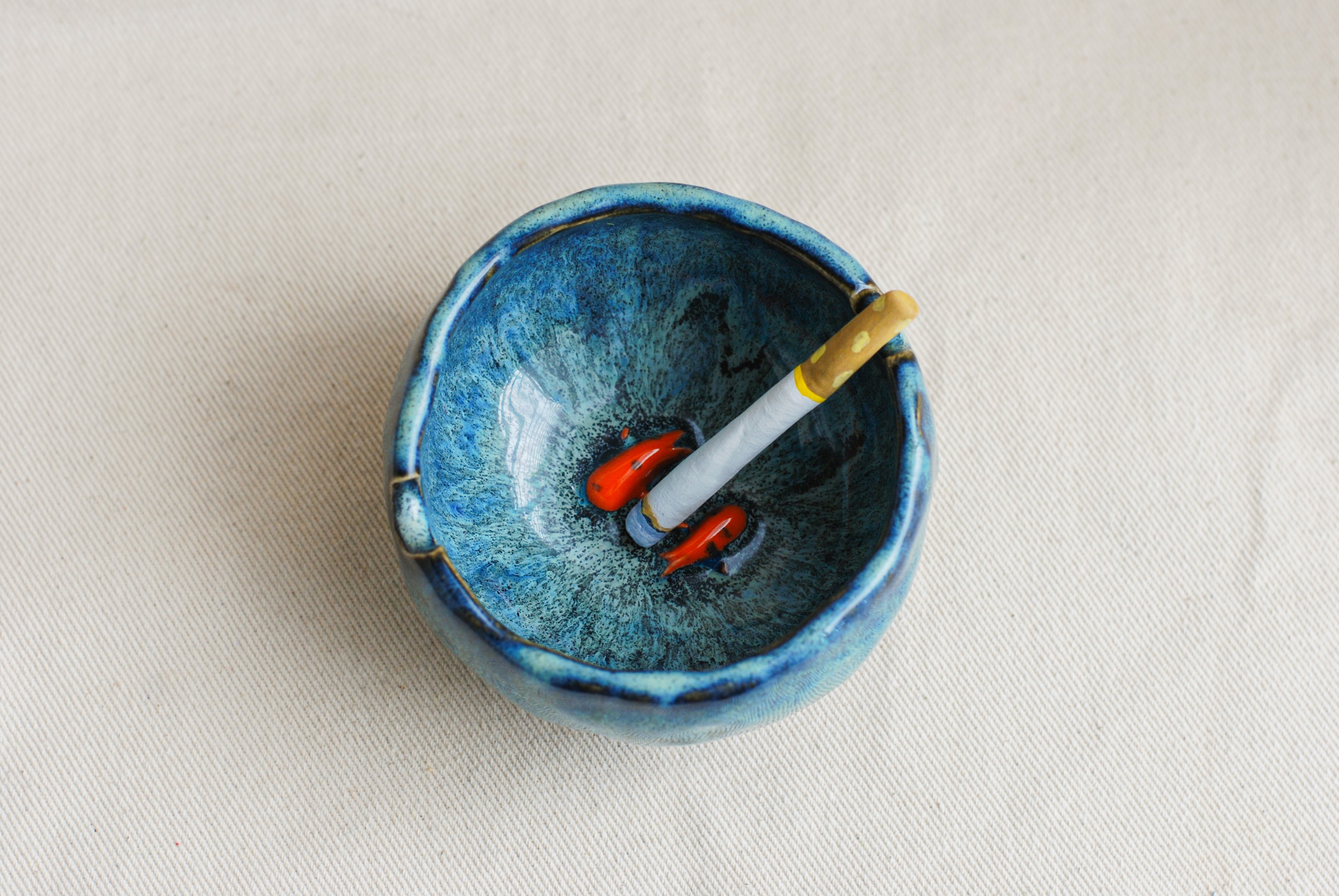 Blue ceramic ashtray with koi fish inspired by a midnight scene kept on a beige background
