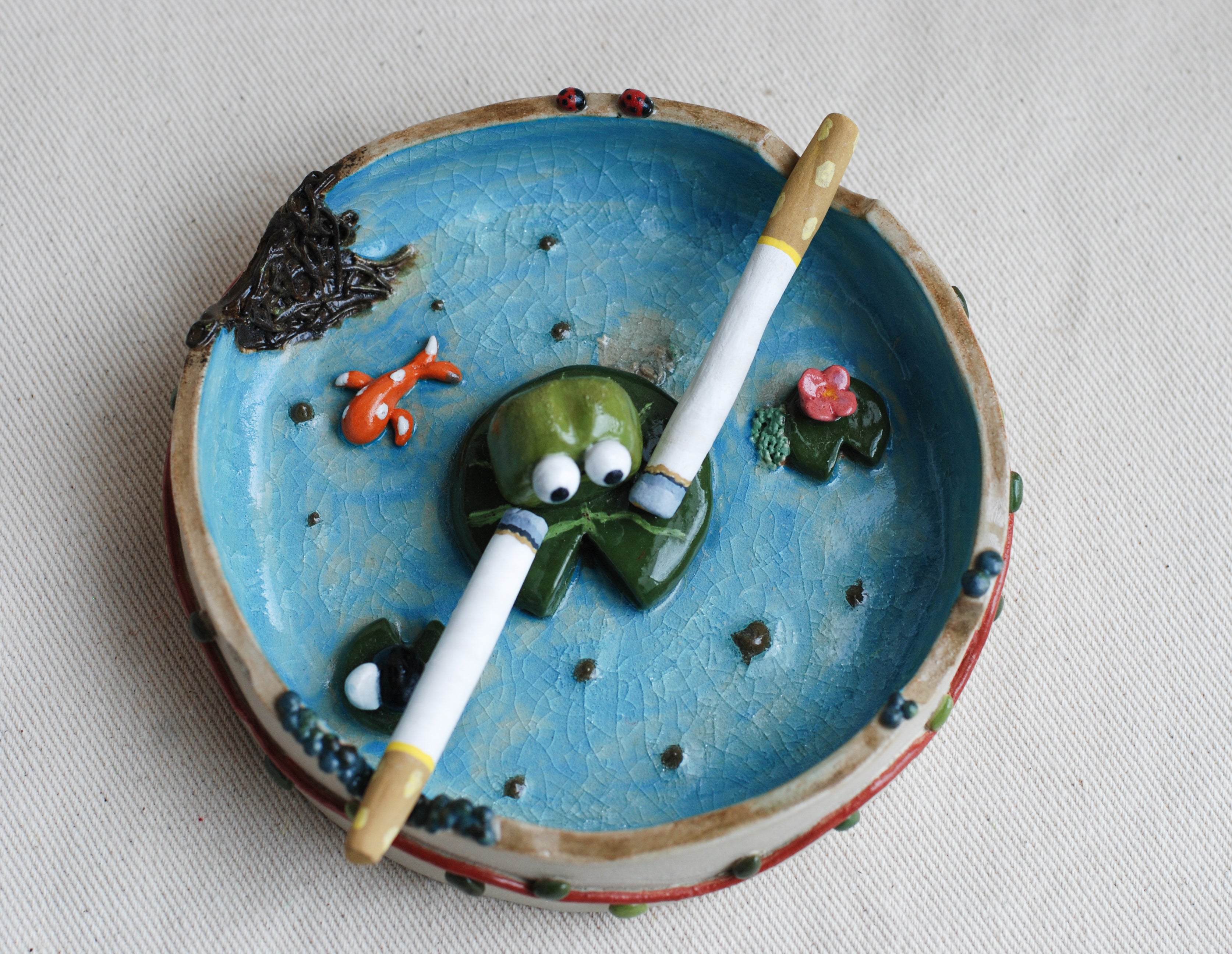 Ceramic ashtray with smoking frog design on a white background made by pipa pots 