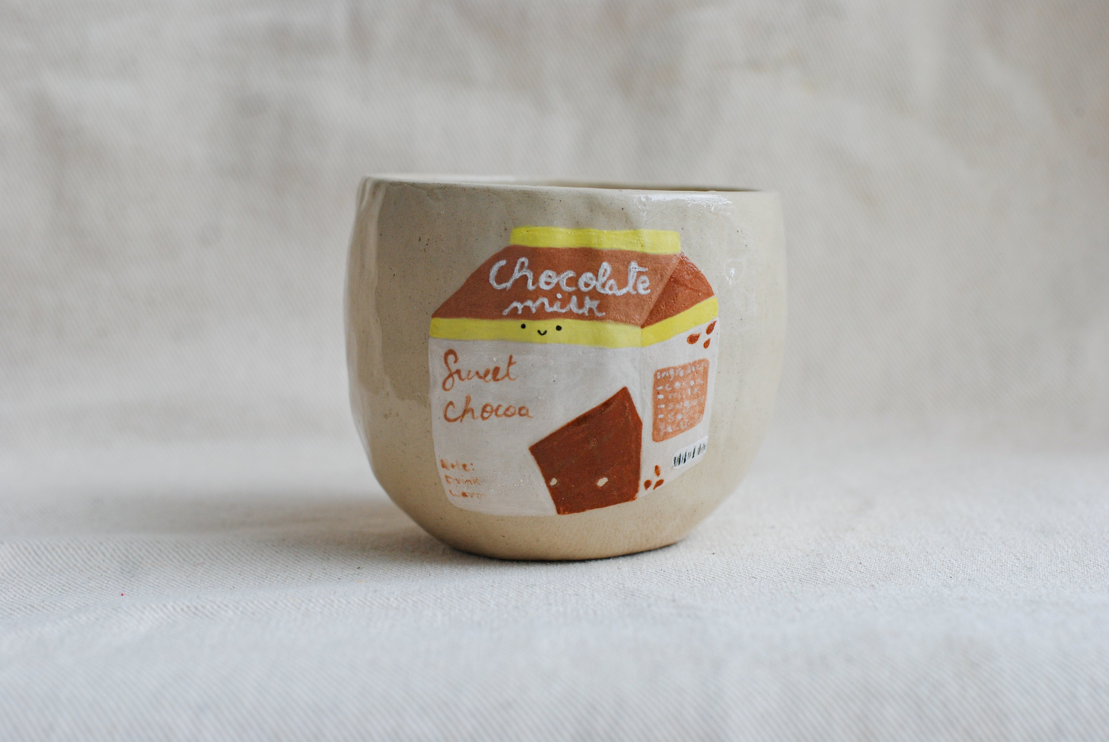 handmade ceramic cup with hand-painted chocolate milk carton illustration, whimsical stoneware