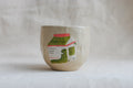 handmade ceramic cup with hand-painted matcha carton illustration, whimsical stoneware