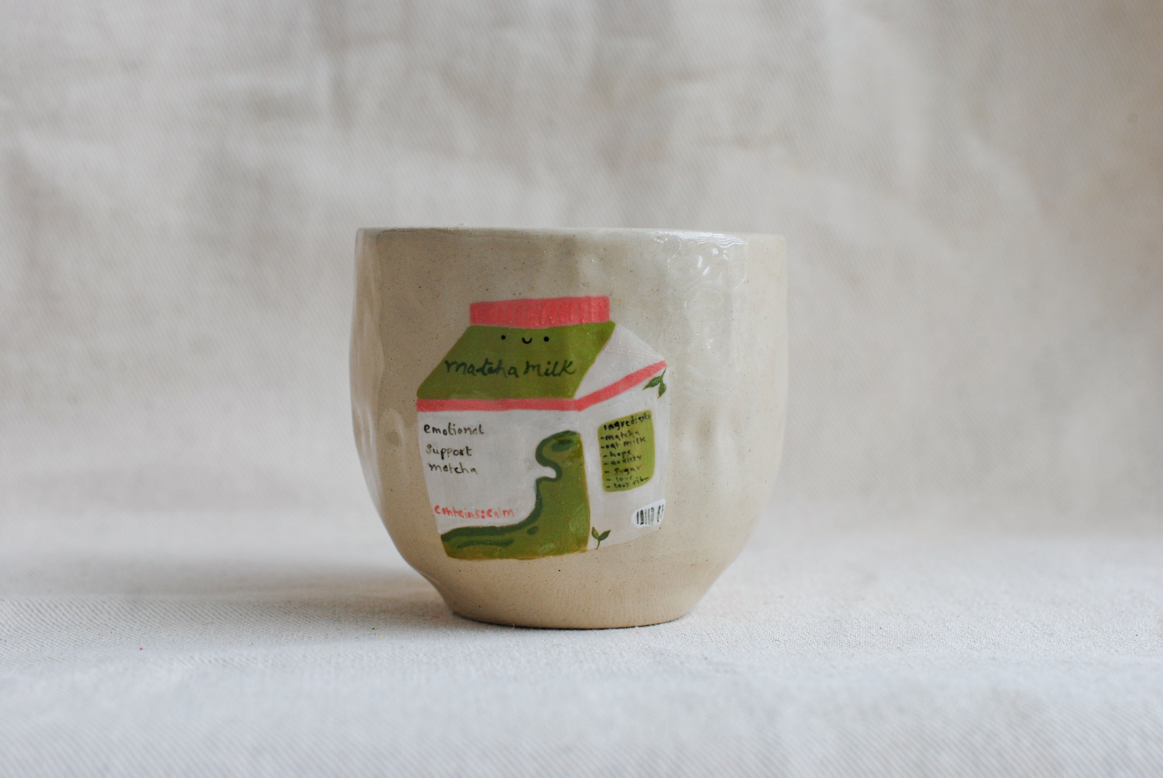 handmade ceramic cup with hand-painted matcha carton illustration, whimsical stoneware