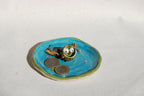Small decorative dish with a frog who has googly eyes on a blue dish with coins. made by pipa pots in the netherlands