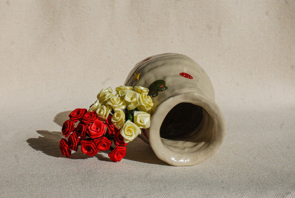 Small ceramic vase with colorful flowers on a beige background