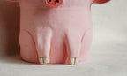 A pink pig-shaped planter or decorative pot shown from the back, with small hooves and a snout detail, photographed against a plain light background.