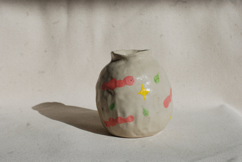 Small ceramic vase with colorful designs on a plain background