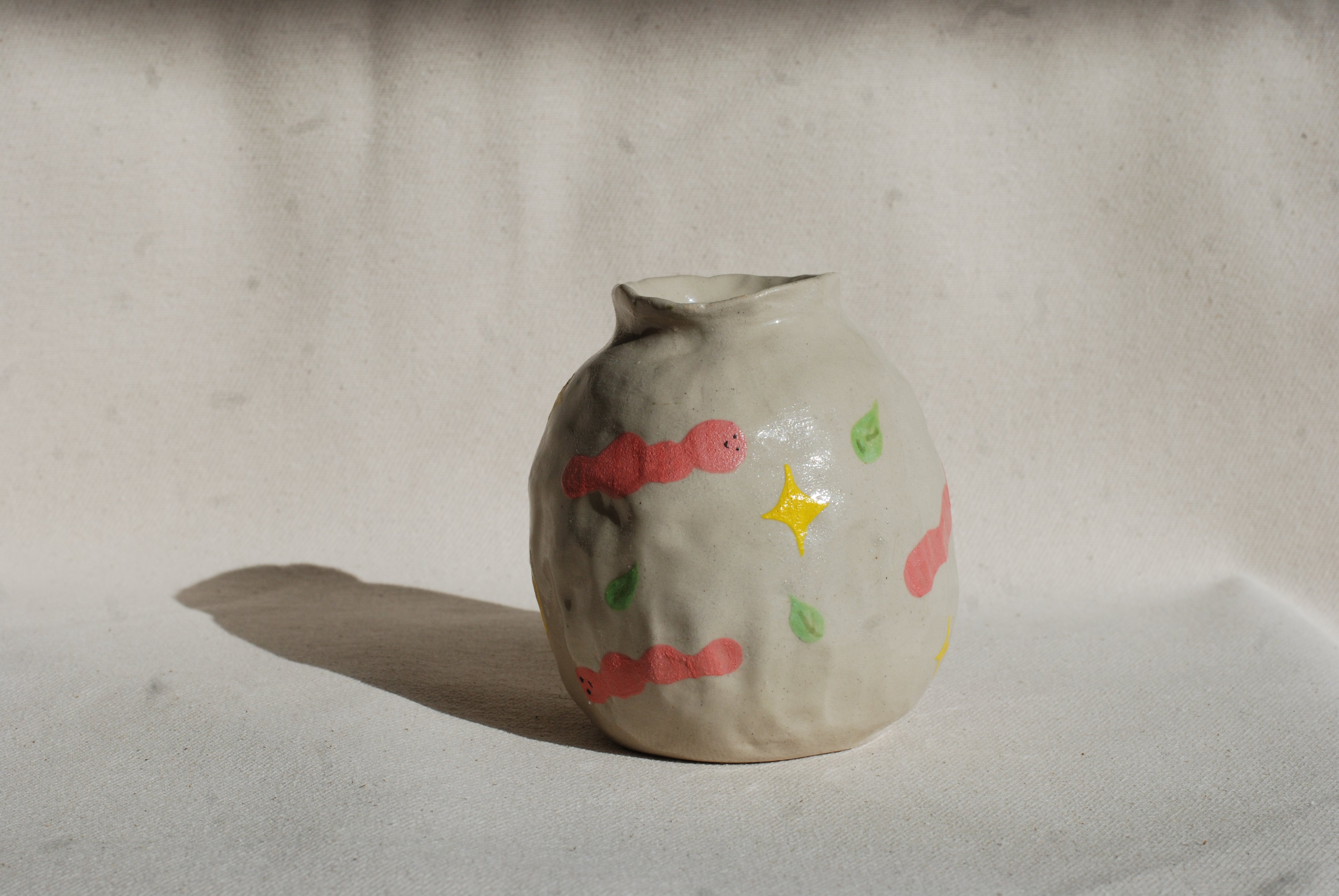 Small ceramic vase with colorful designs on a plain background