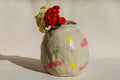 Ceramic vase with colorful star patterns and flowers on a neutral background