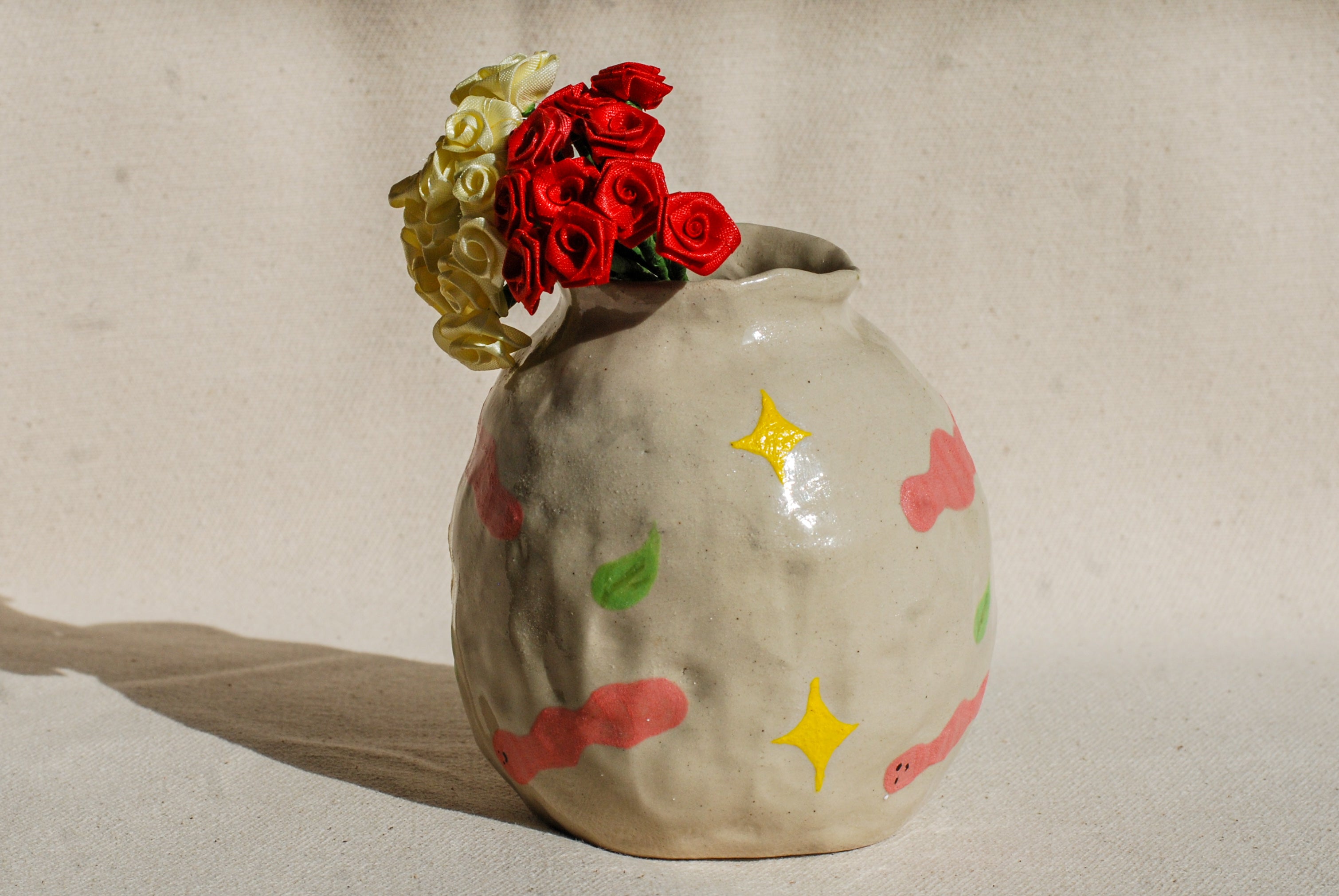 Ceramic vase with colorful star patterns and flowers on a neutral background